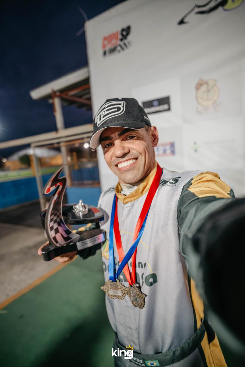 Piloto comemorando com troféu e medalhas
